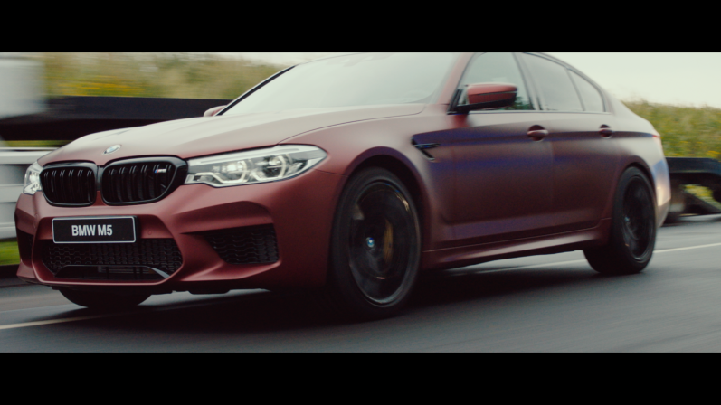NEED FOR SPEED (2018) Roter BMW M5 auf einer Rennstrecke, dynamische Perspektive, sportliches Design.